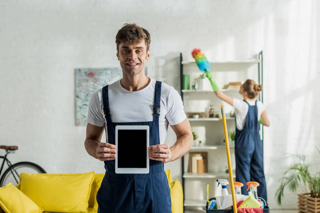 foyer sélectif de nettoyant heureux et beau tenant tablette numérique avec écran blanc
  - Photo, image