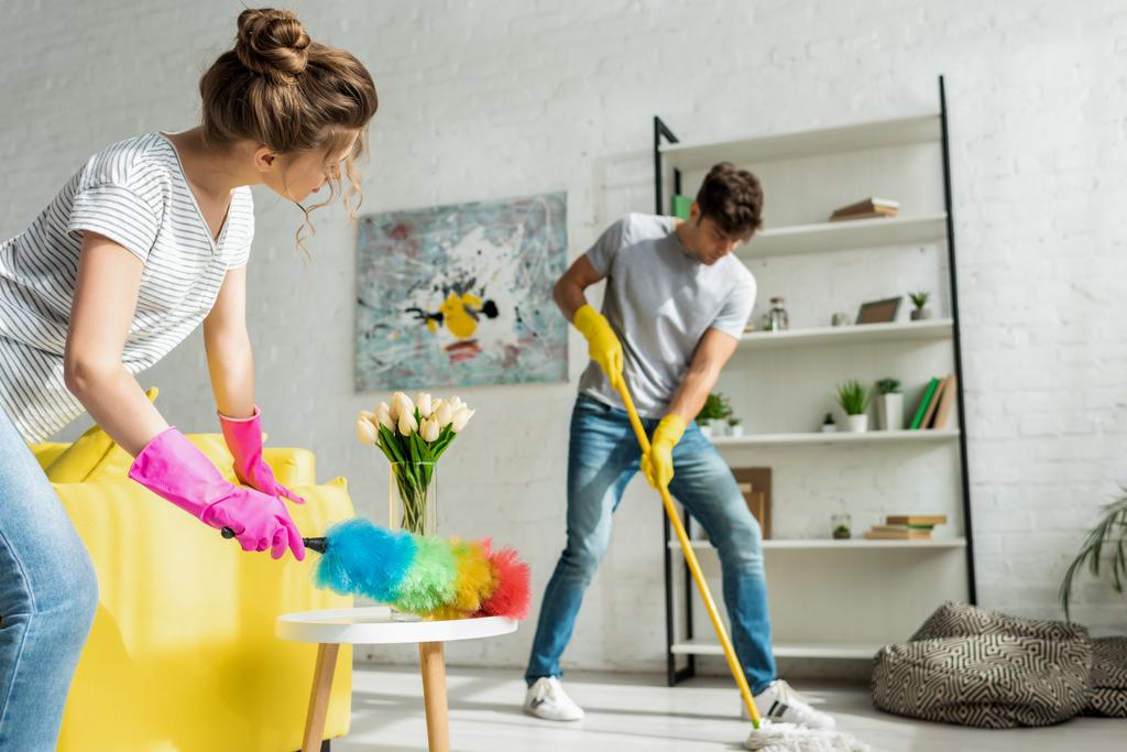 messa a fuoco selettiva di uomo e donna che fanno pulizia di primavera in appartamento
  - Foto, immagini