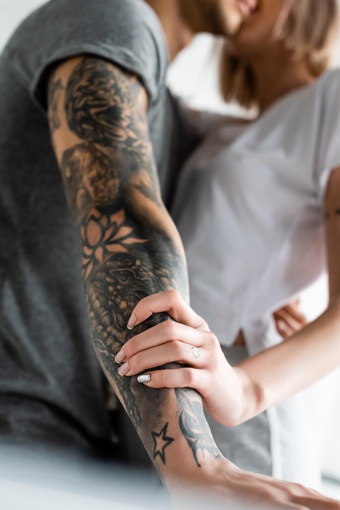 Selective focus of woman touching hand oh tattooed boyfriend at home  - Photo, Image