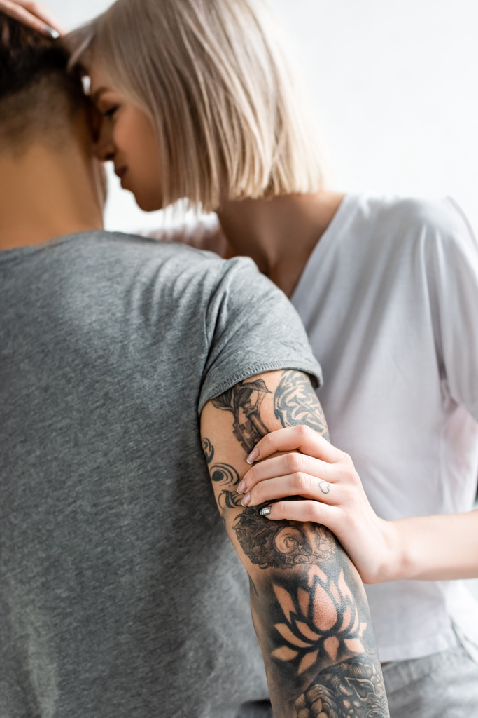 Selectieve focus van aantrekkelijke vrouw aanraken getatoeëerd vriendje geïsoleerd op wit - Foto, afbeelding