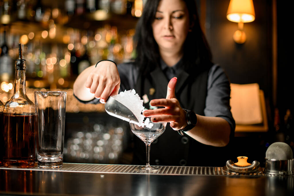 Bartender derramando cubos de gelo em vidro no balcão de bar
. - Foto, Imagem
