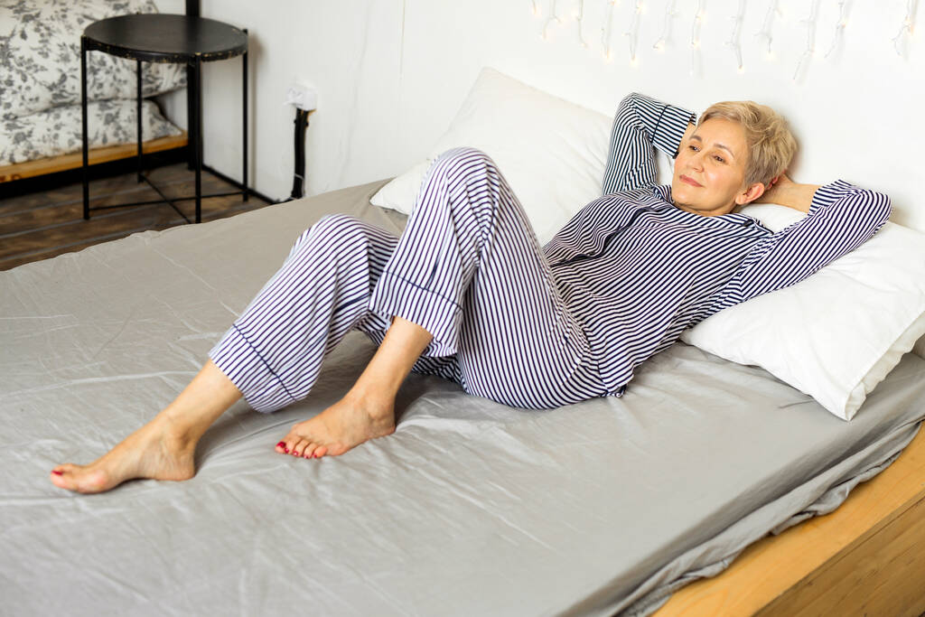 hermosa anciana en pijama se encuentra en la cama
 - Foto, imagen