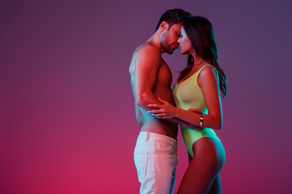 性的若いカップルの側のビューを受け入れ、グラデーションで紫色の背景にキス - 写真・画像