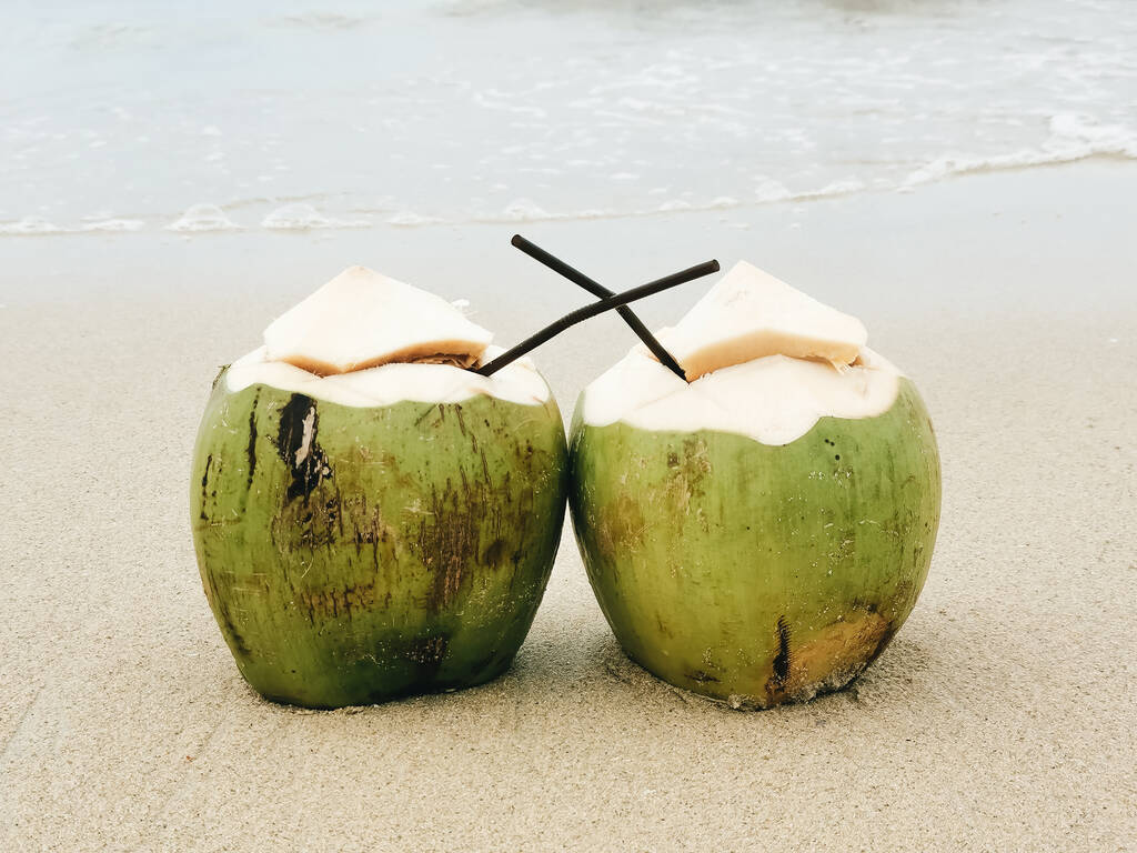 Two coconuts with a tube stand on the beach, Paradise island, Thailand - Photo, Image