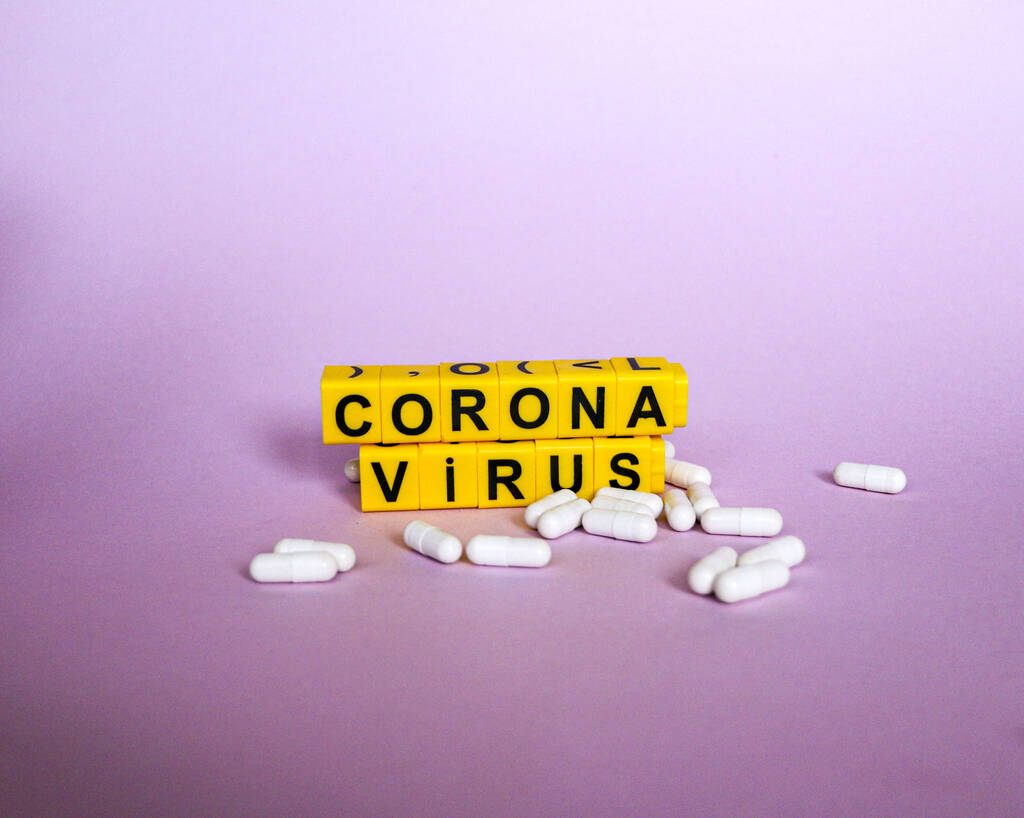 inscription coronavirus from yellow children`s plastic letters on a pink background. - Photo, Image
