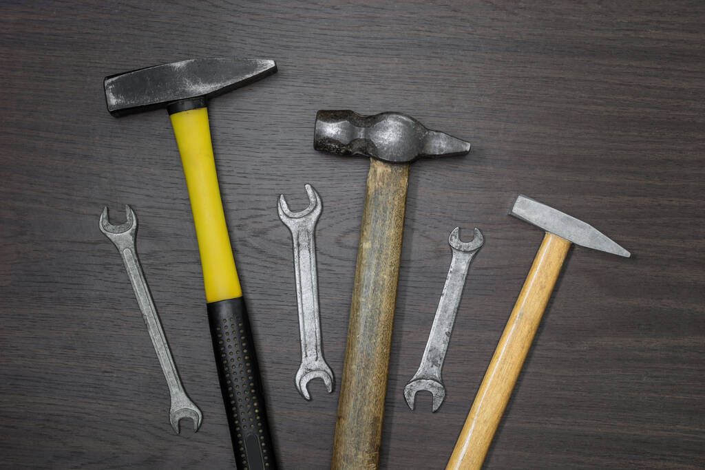 Três martelos e três chaves velhas na mesa de madeira marrom escuro
 - Foto, Imagem