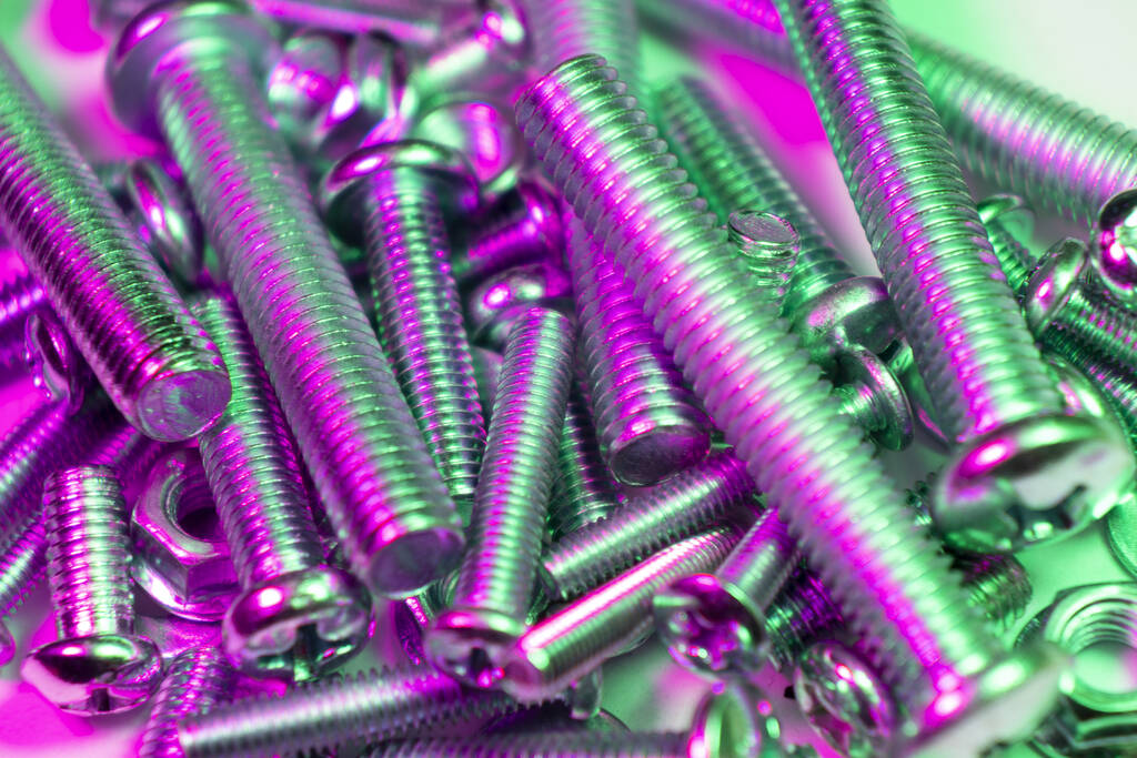 Metal bolts and nuts  in a row background. Chromed screw bolts and nuts in green and pink tones. Steel bolts and nuts pattern. Set of Nuts and bolts. Tools for work. - Photo, Image