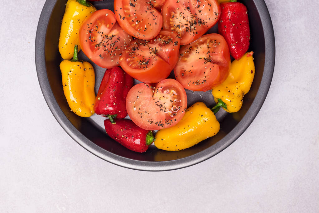 Großer schwarzer Teller mit Gemüse Teller mit reifen Paprika und Tomaten mit Gewürzen Grillfertig Vegetadian Gesundes Speisesaitenöl - Foto, Bild