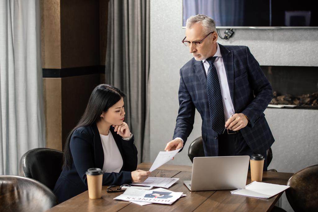 homme d'affaires pointant du doigt le papier et parlant avec une femme d'affaires asiatique lors d'une réunion d'affaires
  - Photo, image