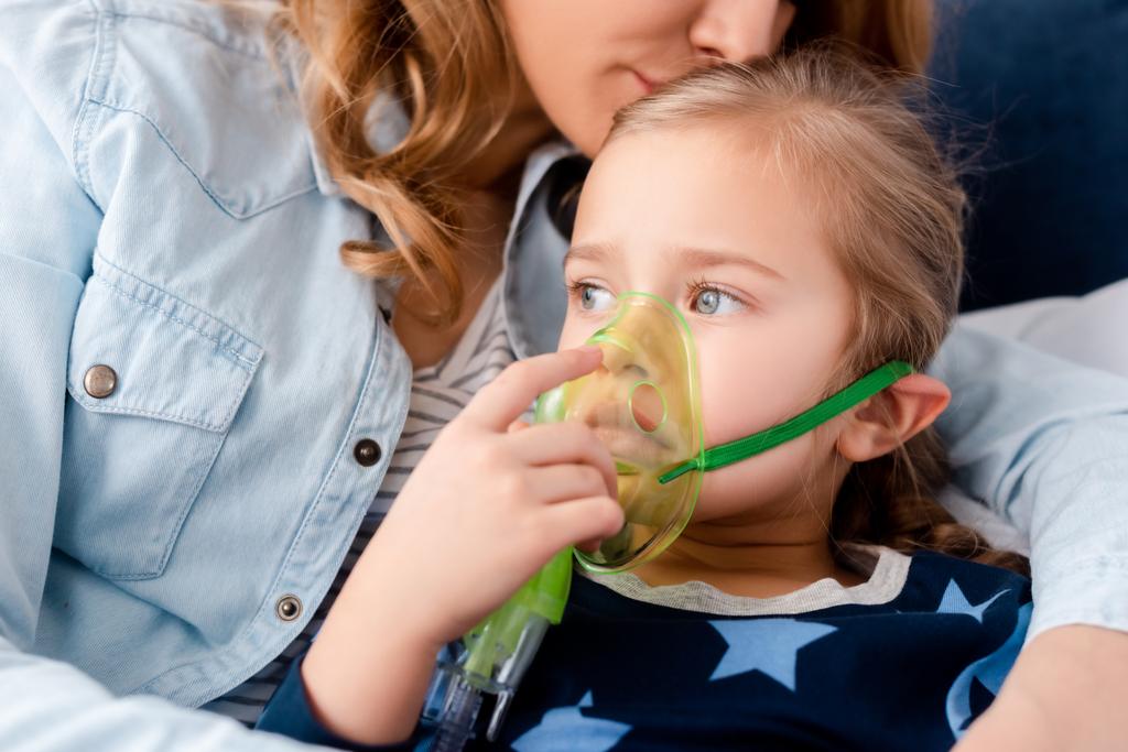 madre besar hija asmática en máscara respiratoria
  - Foto, imagen