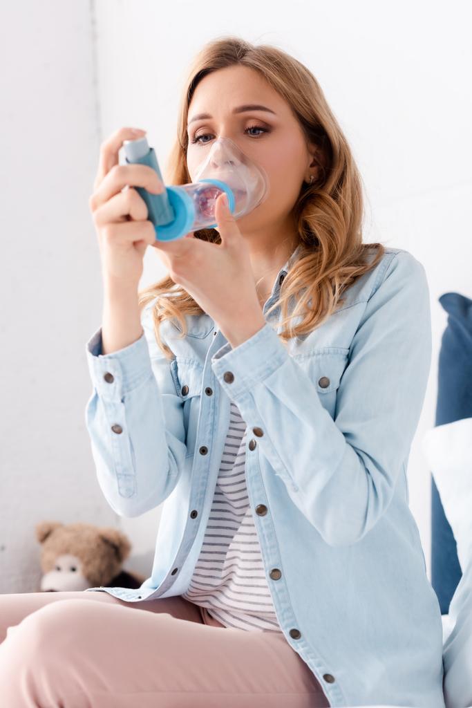 selective focus of sick woman with asthma using inhaler with spacer  - Photo, Image
