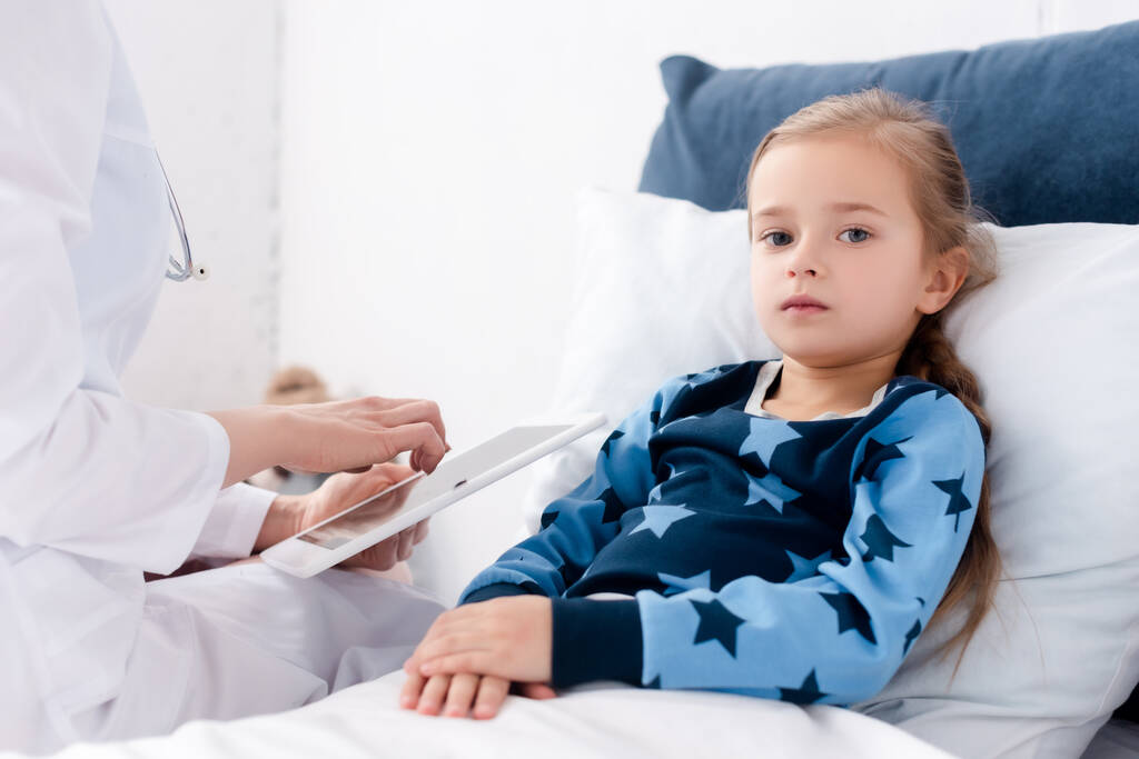 orvos fehér köpenyben tartja digitális tabletta közelében beteg gyerek  - Fotó, kép