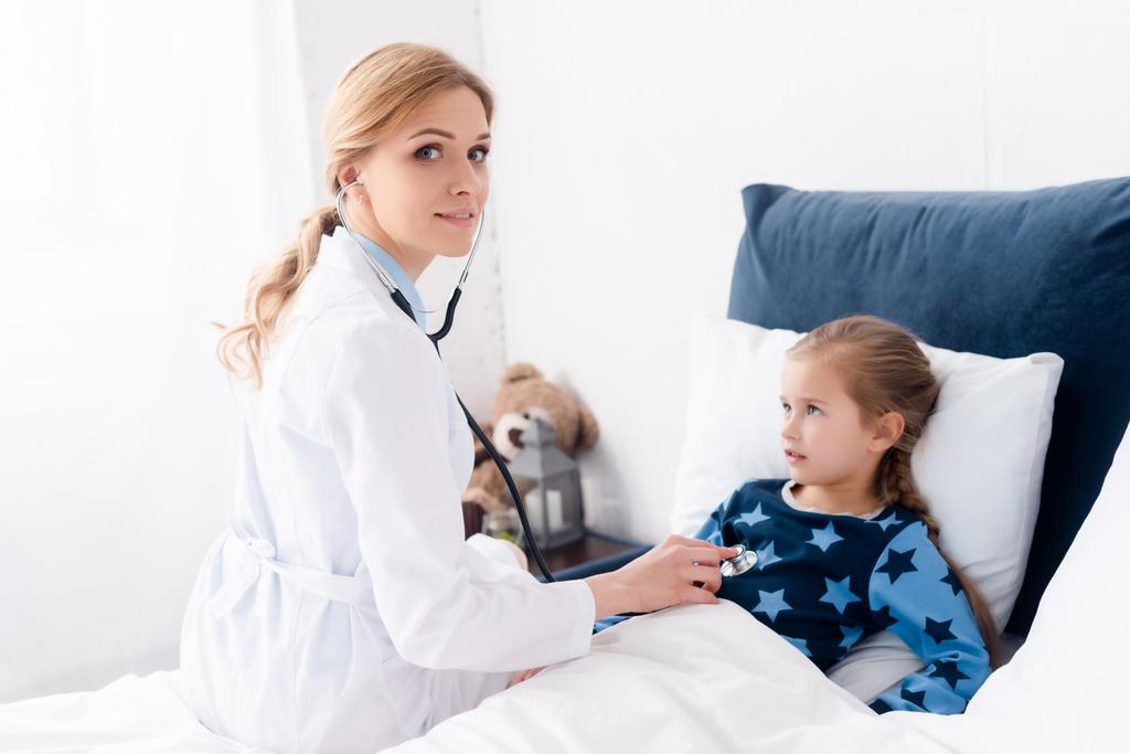 kaunis lääkäri tutkii sairas lapsi makuuhuoneessa
  - Valokuva, kuva