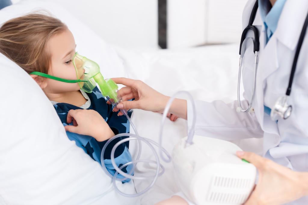 lekarz dotykający maski oddechowej u astmatycznego dziecka stosującego inhalator sprężarkowy  - Zdjęcie, obraz