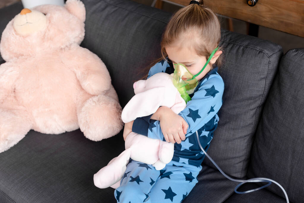 bambino asmatico utilizzando maschera respiratoria mentre abbraccia giocattolo morbido
  - Foto, immagini