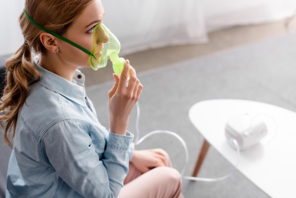 foco seletivo da mulher asmática em máscara respiratória usando inalador compressor
  - Foto, Imagem