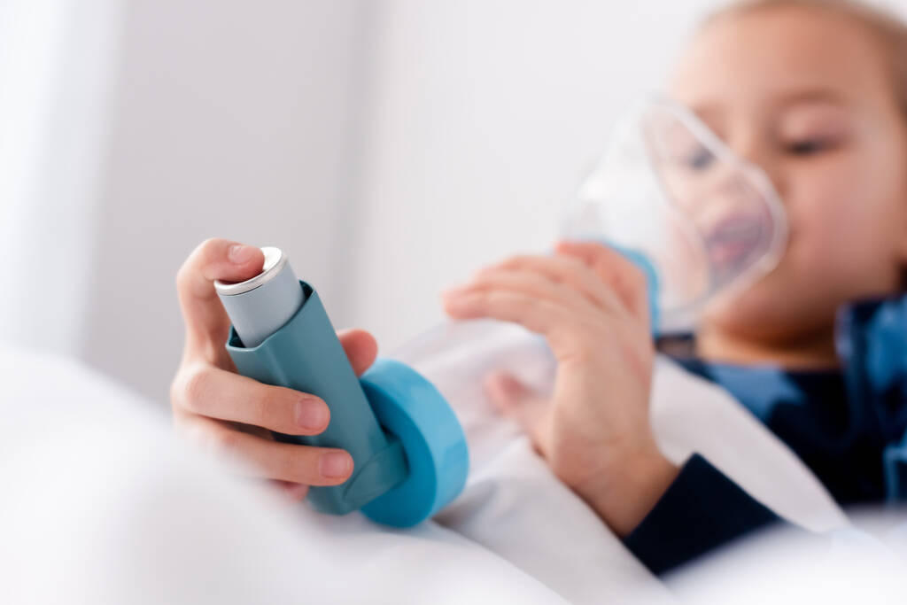 enfoque selectivo del niño enfermo utilizando inhalador con espaciador
  - Foto, imagen