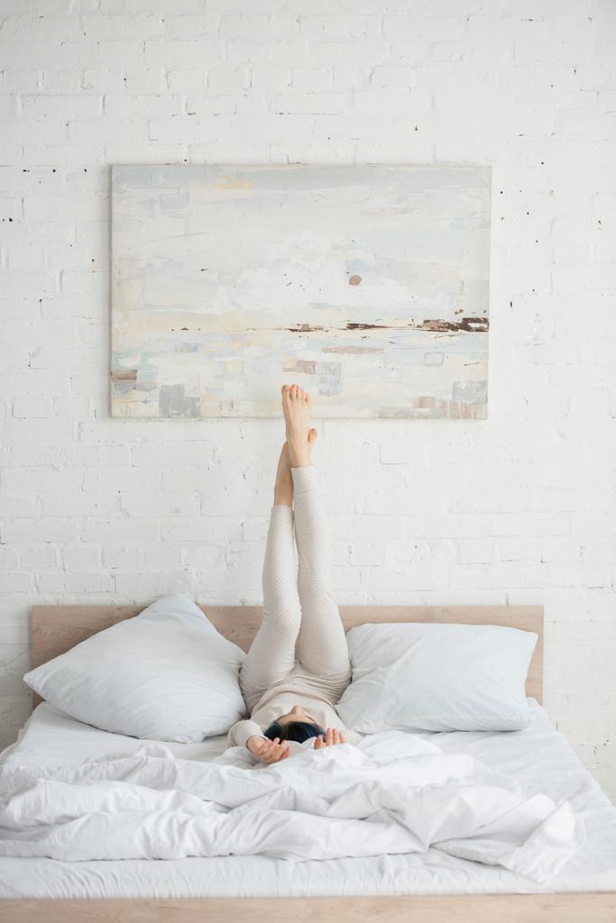 Nainen värikkäät hiukset ja nosti jalat makaa sängyssä makuuhuoneessa
 - Valokuva, kuva