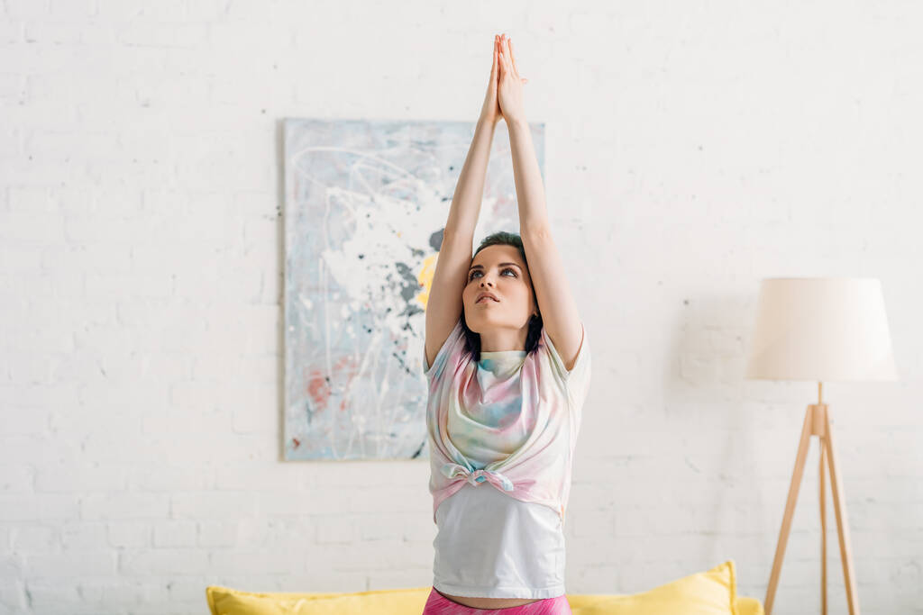 Жінка з барвистим волоссям і зігнутими руками робить йогу асан у вітальні
 - Фото, зображення