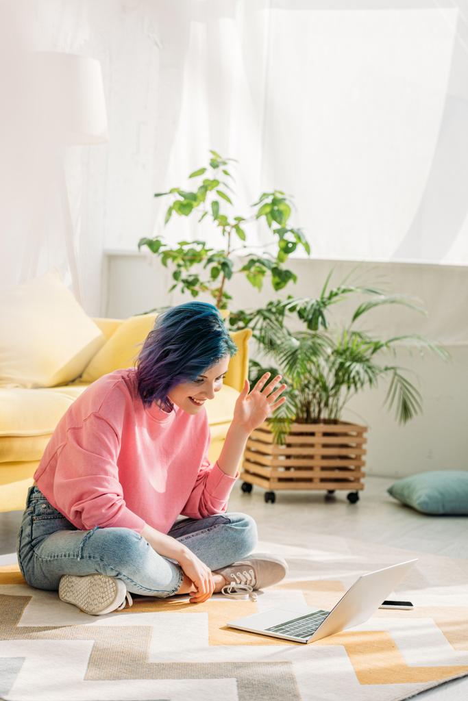 Girl with colorful hair waving hand, smiling and making video call on floor - Photo, Image