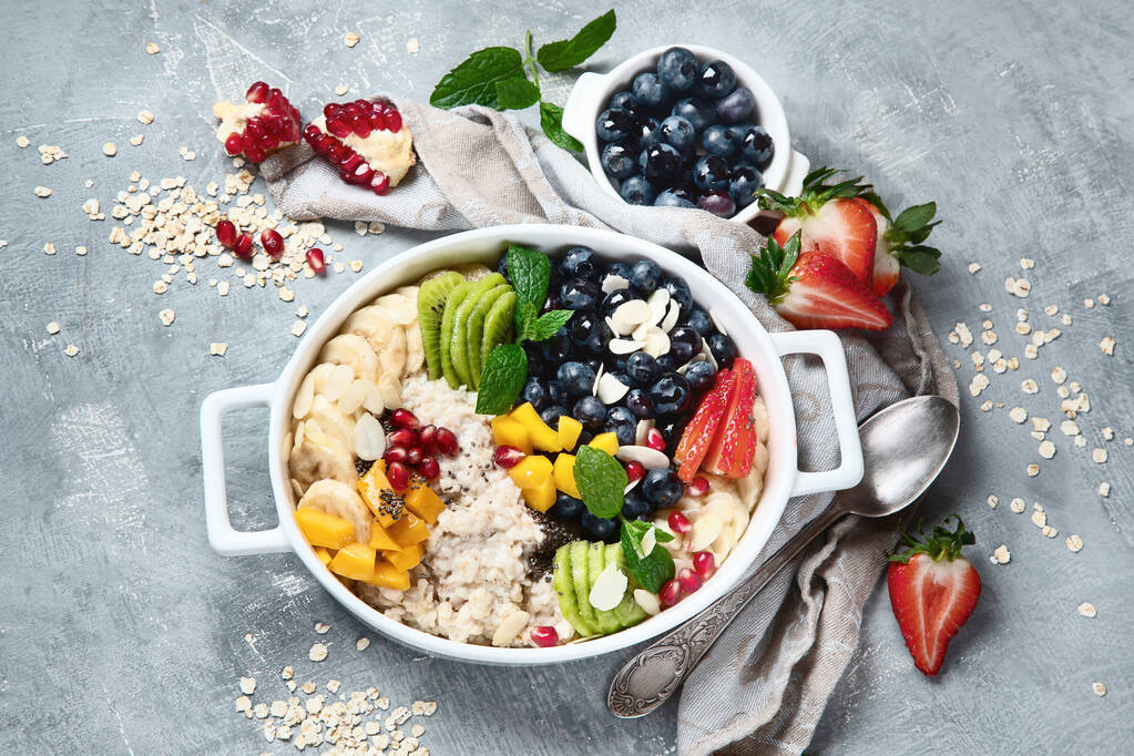 Porridge di farina d'avena con bacche e frutta su fondo grigio. Colazione salutare con vitamine e antiossidanti. Vista dall'alto
 - Foto, immagini