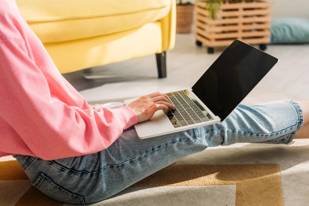 Vista recortada del freelancer trabajando con portátil y sentado en el suelo en la sala de estar
 - Foto, imagen