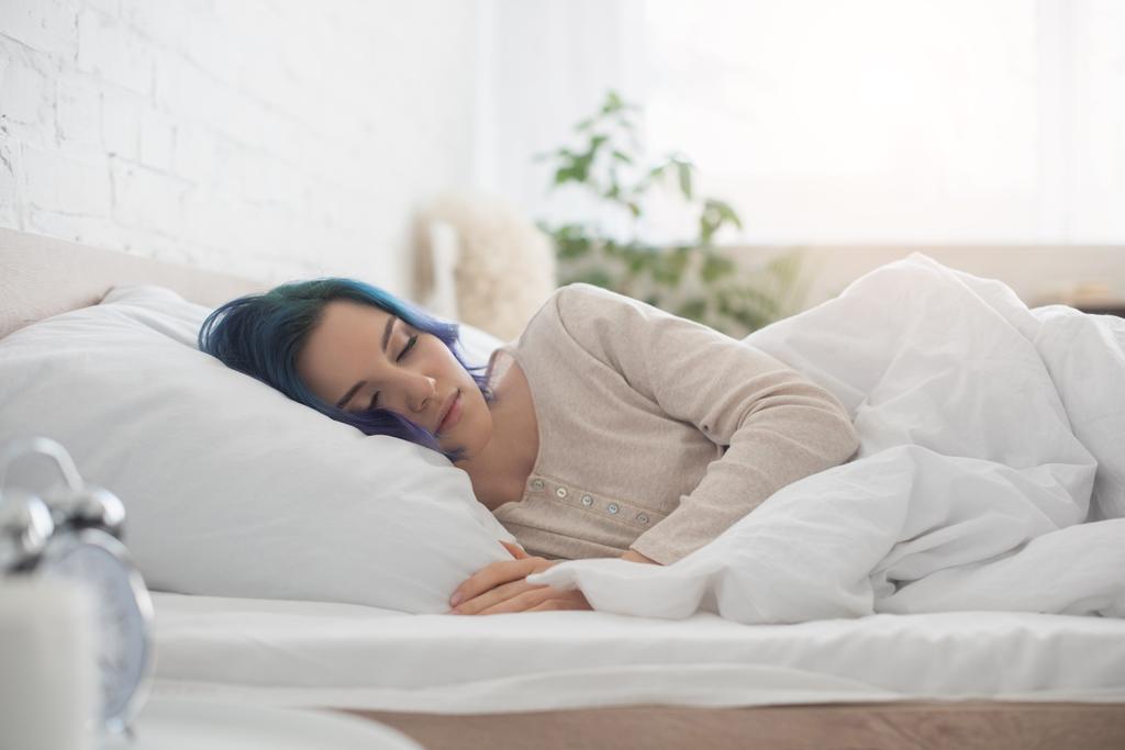 Valikoiva painopiste naisen värikkäitä hiuksia nukkumassa sängyssä makuuhuoneessa
 - Valokuva, kuva