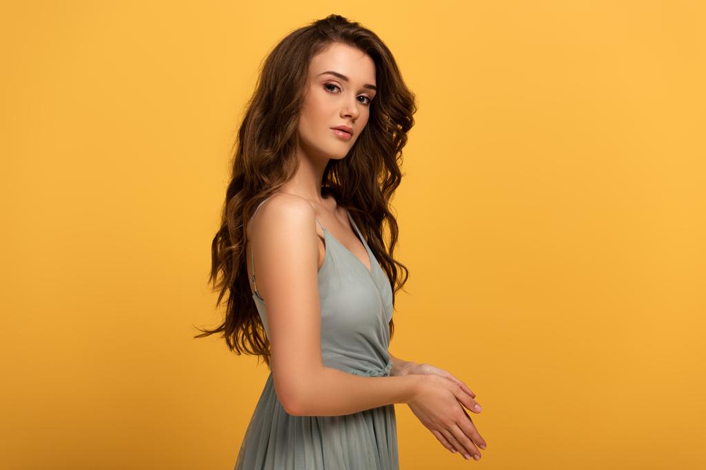 attractive spring girl with long hair in dress isolated on yellow - Photo, Image
