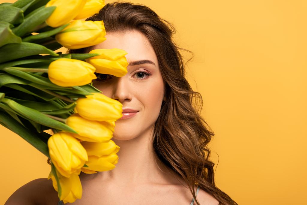 улыбающаяся девушка с цветами тюльпана изолированы на желтый
 - Фото, изображение