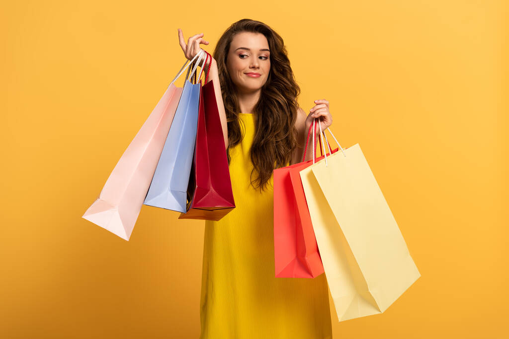 gyönyörű mosolygós lány tavaszi ruha gazdaság bevásárló táskák sárga - Fotó, kép