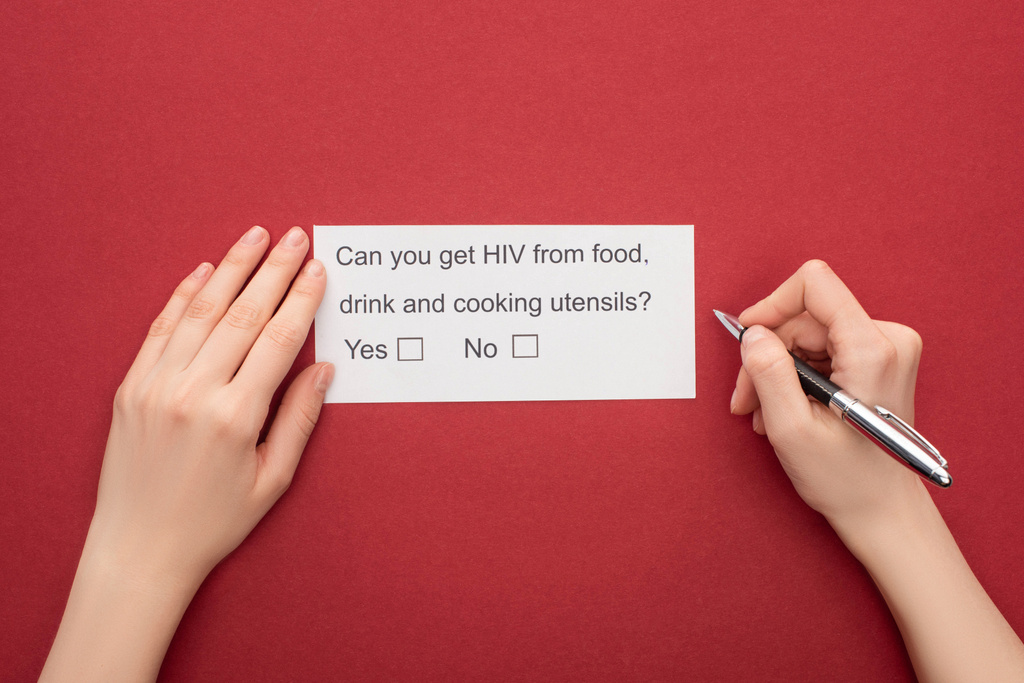 kivágott nézet a HIV-kérdőívet piros alapon kitöltő nőről - Fotó, kép