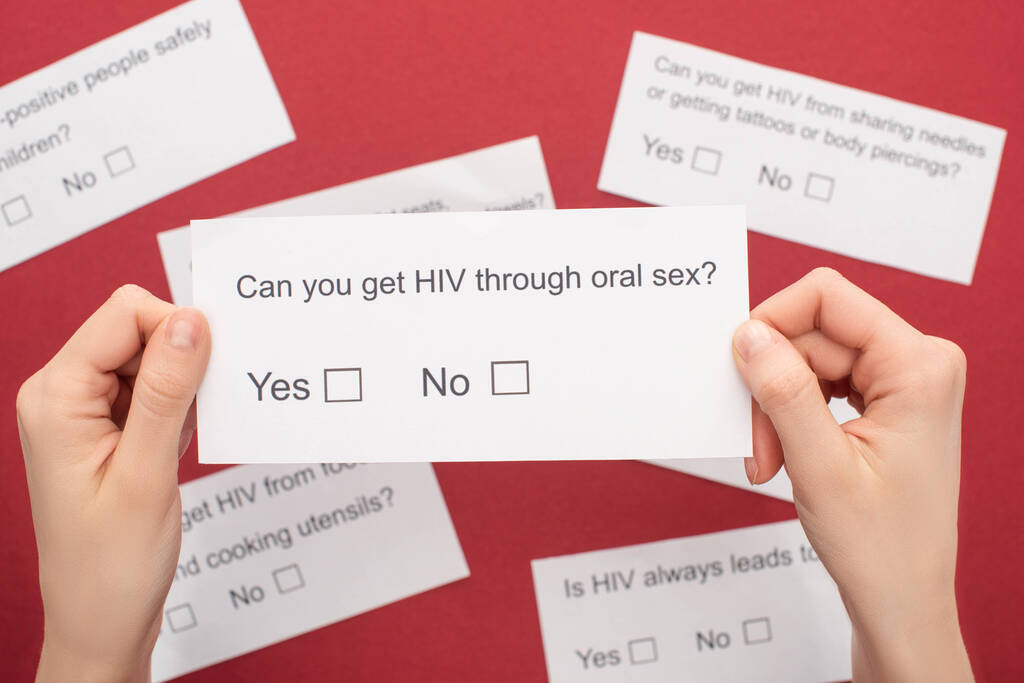 частичный взгляд женщины, держащей анкету по ВИЧ на красном фоне
 - Фото, изображение