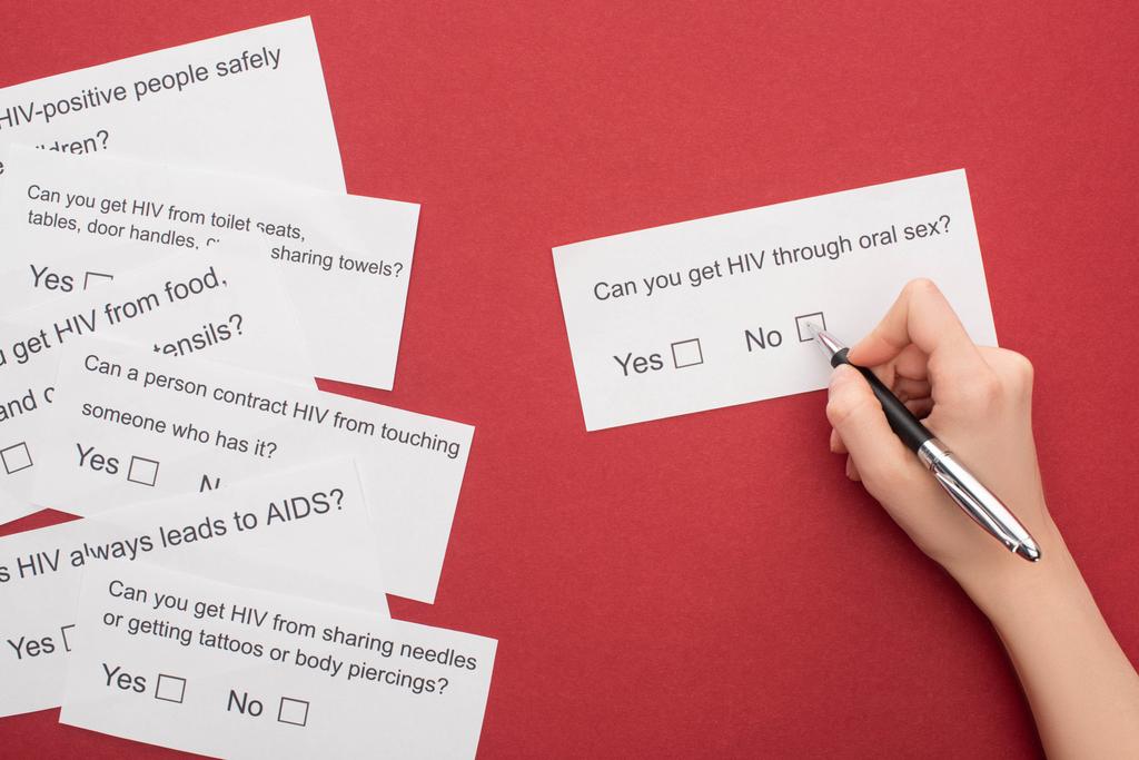 partial view of woman answering HIV questionnaire on red background - Photo, Image
