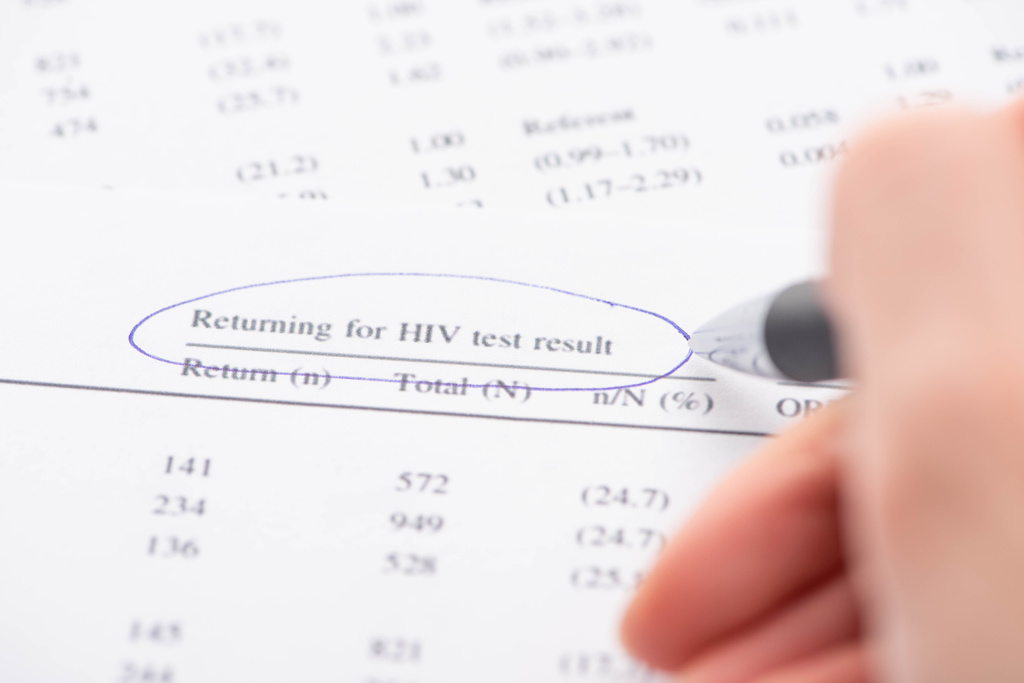 Ausgeschnittene Ansicht einer Frau, die mit Stift die Rückgabe des HIV-Testergebnisformulars markiert - Foto, Bild