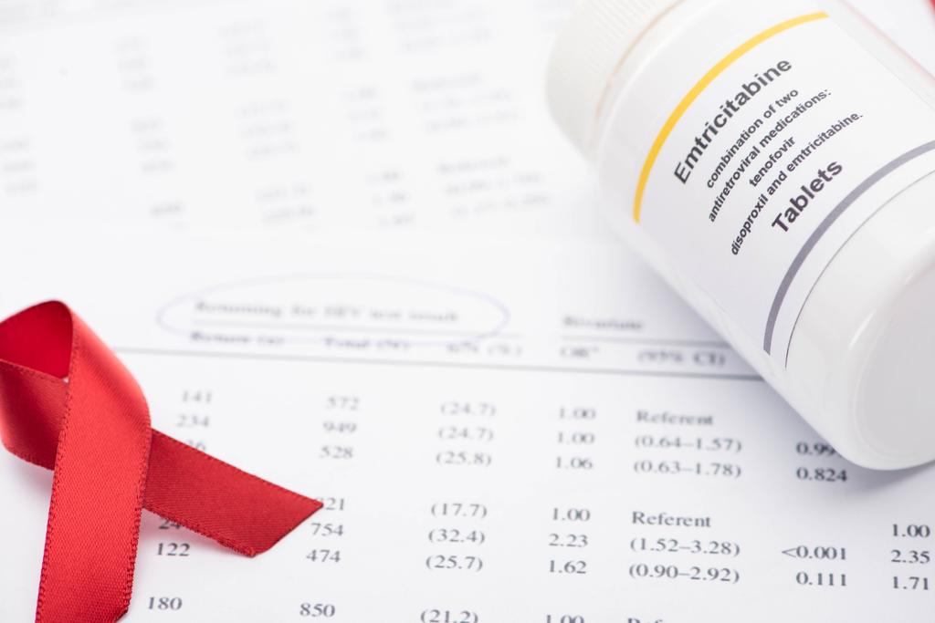 close-up zicht op terugkeer voor hiv-testresultaatvorm met pen, bewustmakingslint en container met emtricitabine tabletten  - Foto, afbeelding