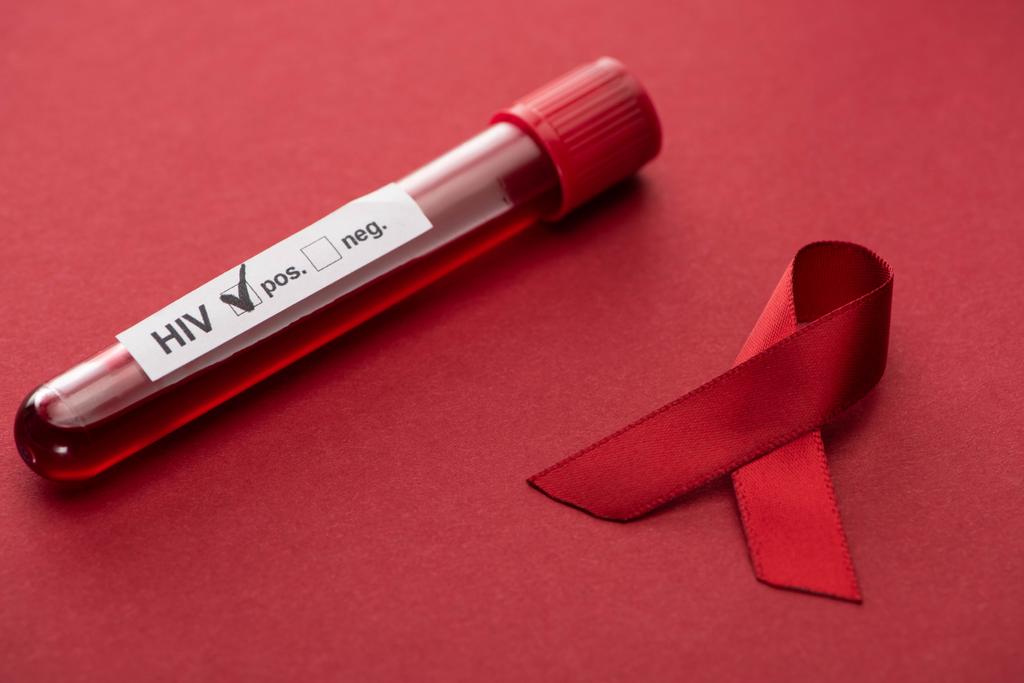 ruban d'aides de sensibilisation rouge et test d'échantillon de sang hiv positif sur fond rouge
 - Photo, image