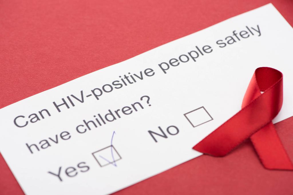 papieren kaart met hiv-vragenlijst met bewustmakingslint op rode achtergrond - Foto, afbeelding