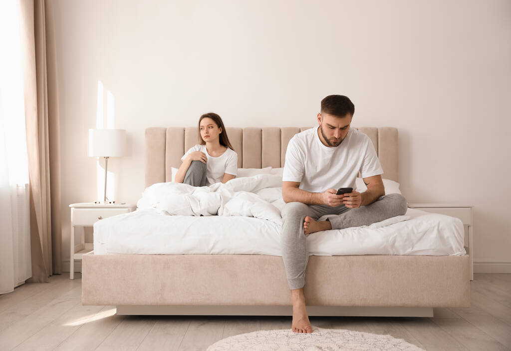 Jeune homme préférant smartphone sur sa petite amie sur le lit à la maison. Problèmes relationnels
 - Photo, image