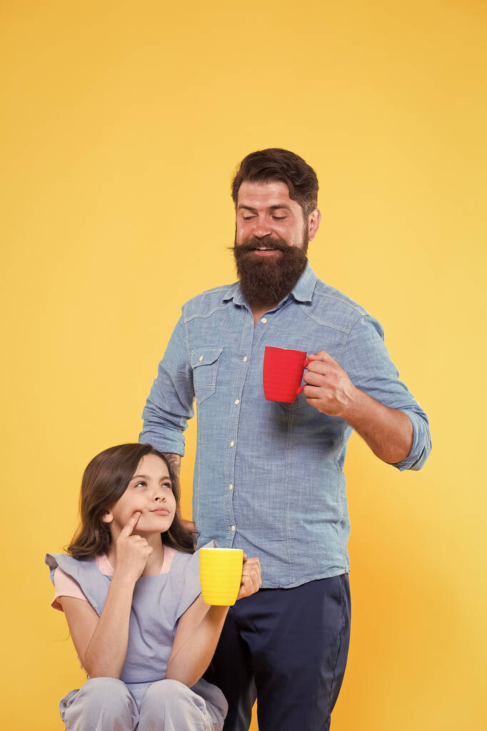 Finom az első korty. A boldog család csészéket tart finom forró itallal. A kis gyermek és apa ízletes ízű kávét fogyaszthatnak. Jó reggelt! Reggeli. Finom és aromás - Fotó, kép