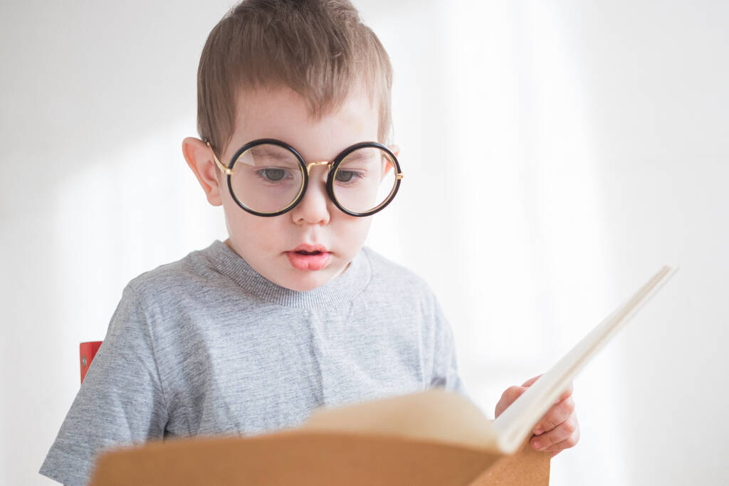 Lindo niño leyendo un libro con gafas. Preescolar inteligente. Regreso al concepto escolar
 - Foto, imagen