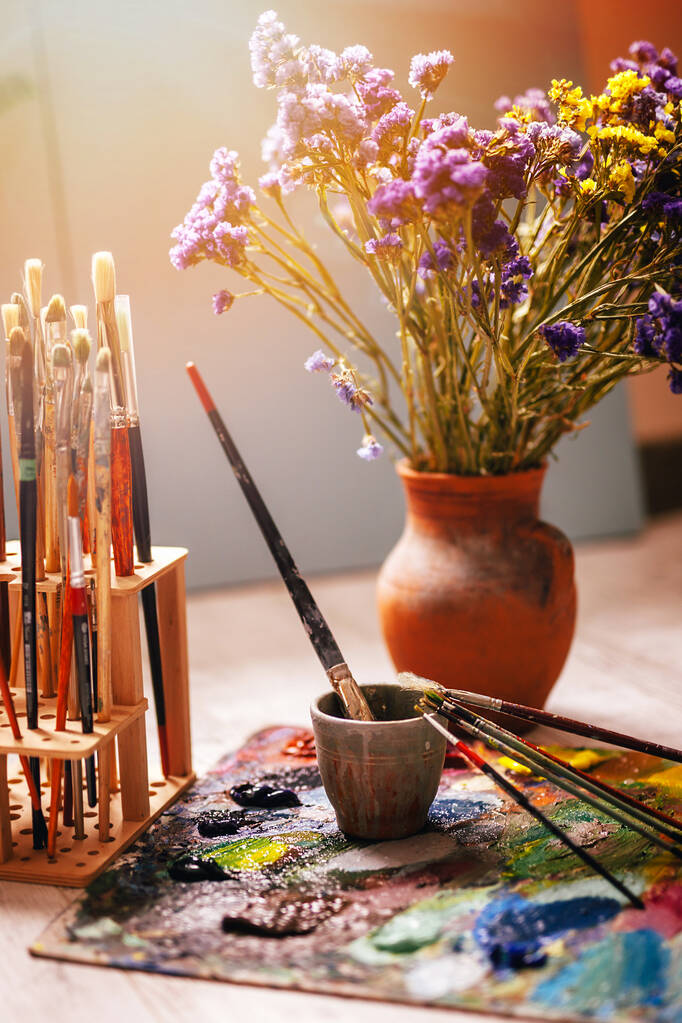 composition with paint brushes and a jug, the concept of the artist with flowers - Photo, Image