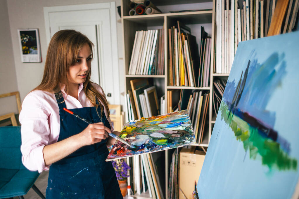 girl stands near the canvas with a palette - Photo, Image