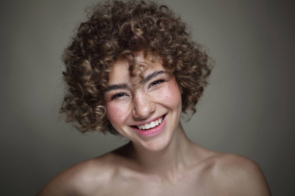 Vintage styl portrét usmívající se krásné mladé pihovaté dívky s kudrnatými vlasy, selektivní zaměření - Fotografie, Obrázek