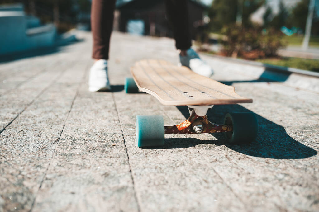 Dışarıdaki bir sörf tahtasının üzerinde spor ayakkabılı kadın bacaklarının yakın çekimi. - Fotoğraf, Görsel