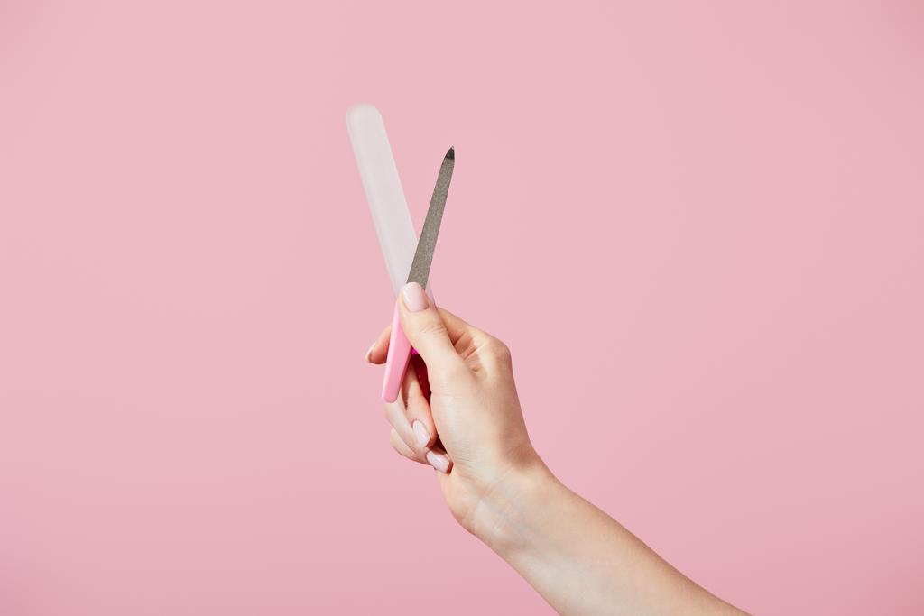 Обрізаний вид жіночої руки з файлами нігтів ізольовані на рожевому
 - Фото, зображення
