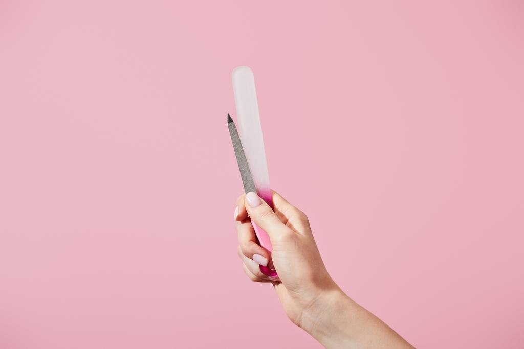 ピンクに隔離された爪のファイルを持つ女性の手の部分的なビュー - 写真・画像