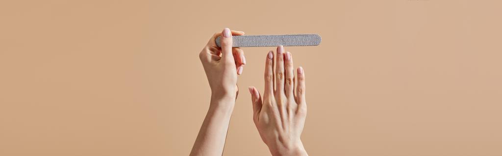 Cropped view of woman filing nail with emery board isolated on beige, panoramic shot - Photo, Image