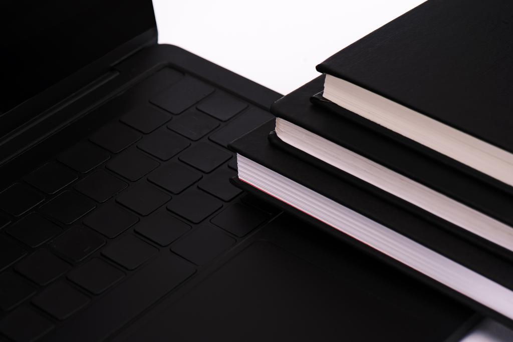 блокноти біля чорного і сучасного ноутбука ізольовані на білому
  - Фото, зображення