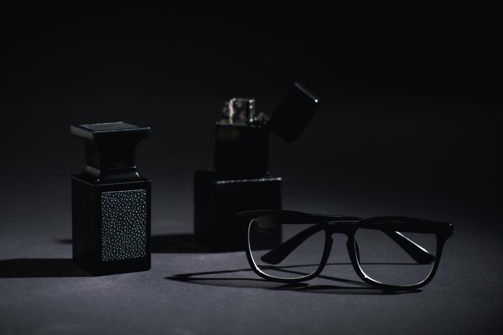 fuoco selettivo di occhiali e bottiglia di profumo vicino accendino sul nero
  - Foto, immagini