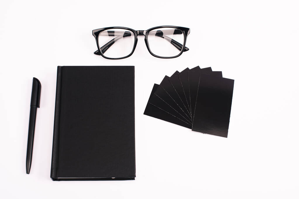 vista superior de cuaderno, bolígrafo, tarjetas en blanco y gafas aisladas en blanco
  - Foto, Imagen